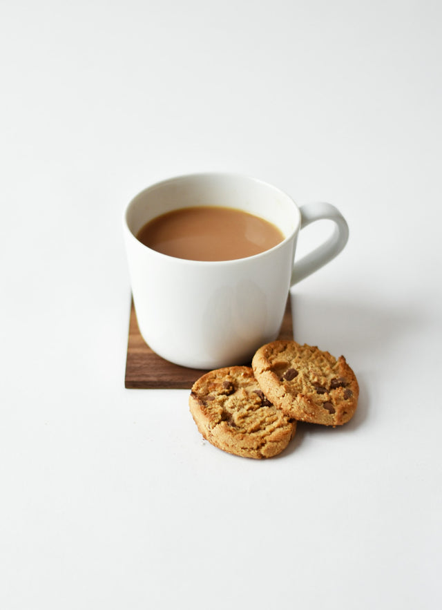 Tasse de thé fumante posée à côté d'une tasse de café sur un plan de travail en bois
